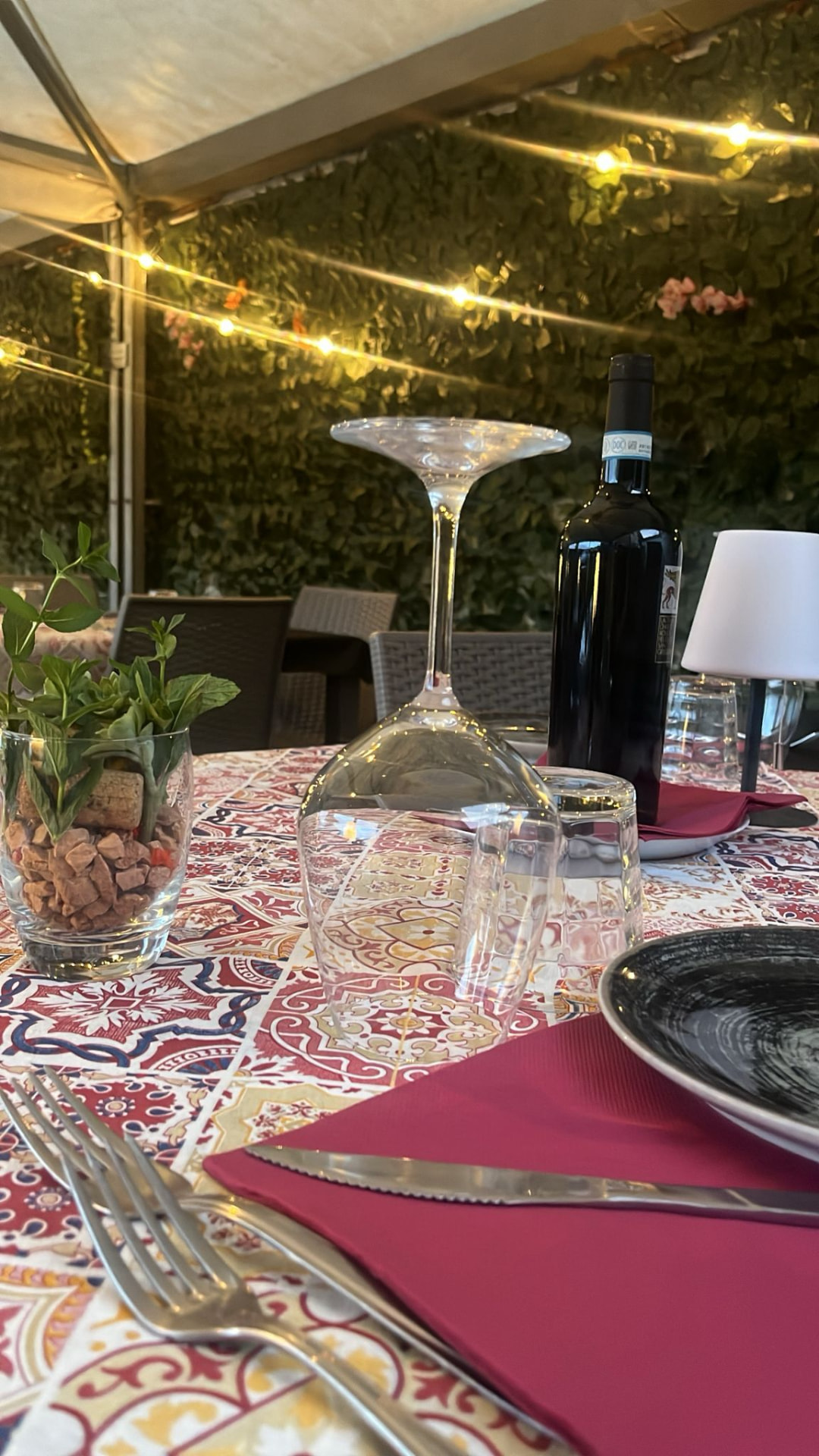 Tavolo all'aperto con luci e bottiglia di vino